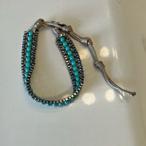 Turquoise, silver, and thick tan thread make up this unique 7” bracelet.